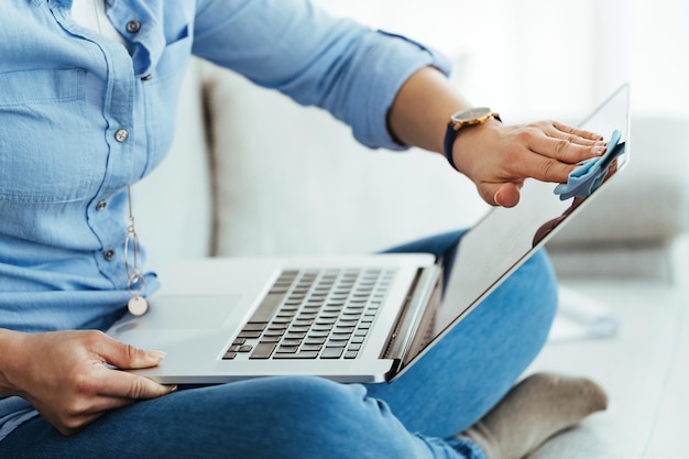 Free photo unrecognizable woman cleaning her laptop with fabric cloth at home