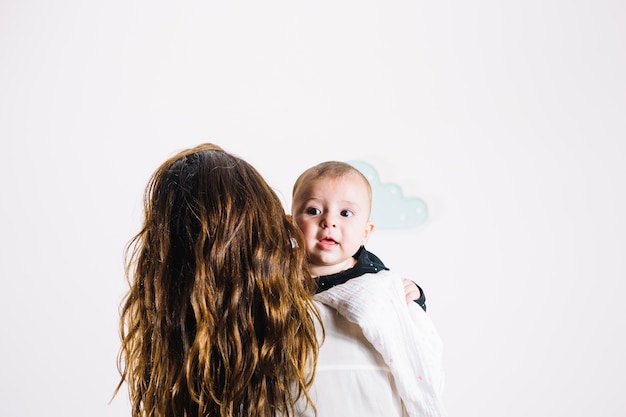 Unrecognizable woman hugging cute baby