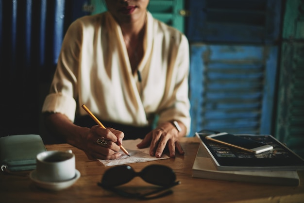 Free Photo unrecognizable woman sitting in cafe and drawing on napking