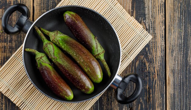 Unripe eggplants in a pan on wooden and placemat,