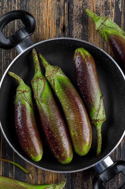 Free photo unripe eggplants in a pan on a wooden.