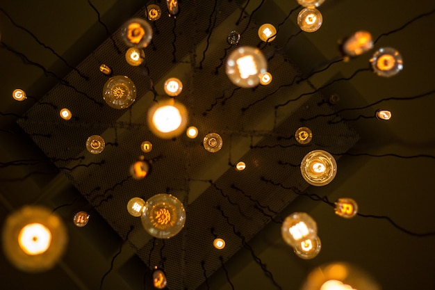 Free photo up-shot of many lights with dim light hanging from the ceiling on wires