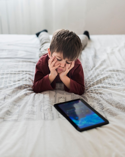 Upset kid in bed with tablet