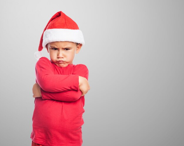 Upset little boy wearing santa claus hat