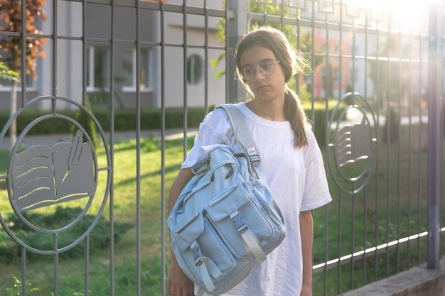 Free Photo upset schoolgirl with backpack near school sunset in the background upset girl