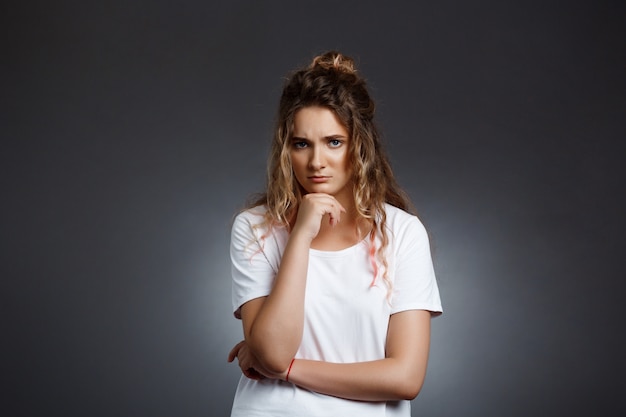 Free photo upset young beautiful girl over grey wall.