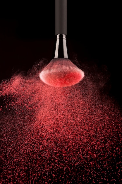 Free photo upside down makeup brush with red powder splash