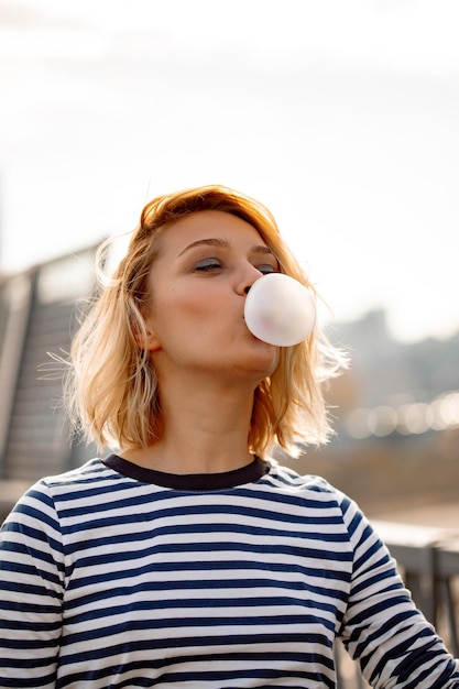 Free photo urban stylish young girl. outdoors emotional portrait of active woman model. healthy lifestyle. fashion look, outdoor hipster portrait. close up portrait of a pretty young girl chewing bubble gum.