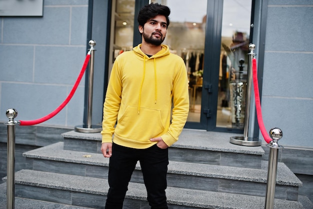 Free photo urban young hipster indian man in a fashionable yellow sweatshirt cool south asian guy wear hoodie