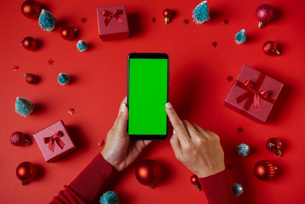 Free photo using smartphone with blank green screen on table with christmas decorations top view