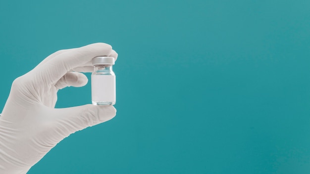 Free photo vaccine bottle held by hand with glove and copy space