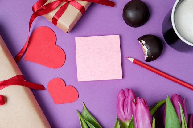 Free Photo valentine background with gift box sweet hearts and tulips on violet table top view flat lay