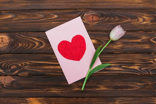 Valentine card and flower on wooden desk 