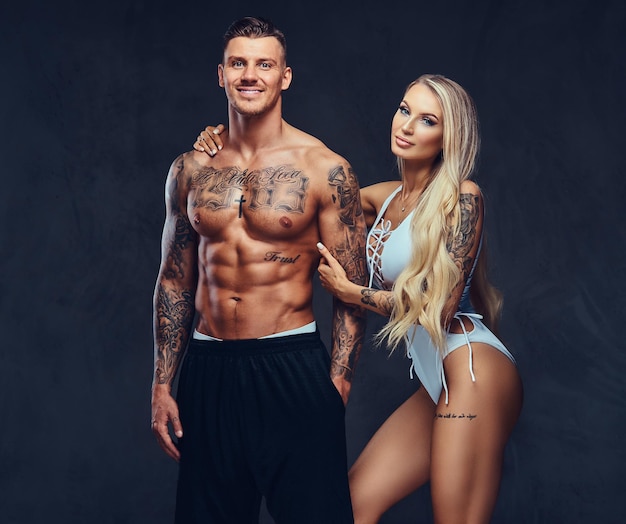 Valentine couple, handsome tattooed male and alluring girl holding hands, posing in studio