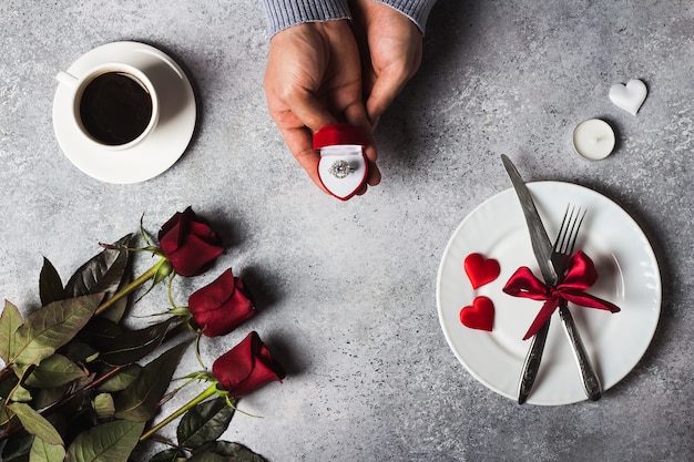 Free photo valentines day romantic dinner table setting man hand holding engagement ring in box marry me