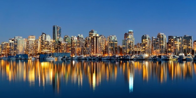 Vancouver downtown architecture and boat with water reflections at dusk panorama