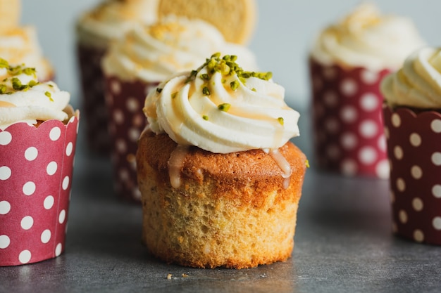 Vanilla cupcakes with cream and caramel on grey table background.