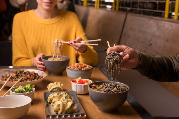 Variety of asian food and bowls of noodles on table