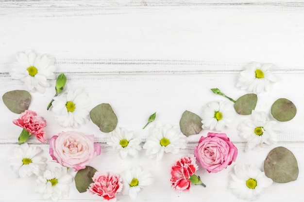 Variety of beautiful fresh flowers over white wooden desk