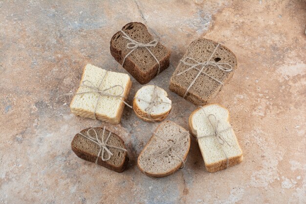 Variety of bread tied with rope on marble background