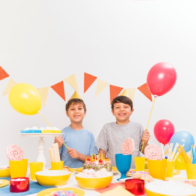 Variety of food on table with two boys holding balloons in party