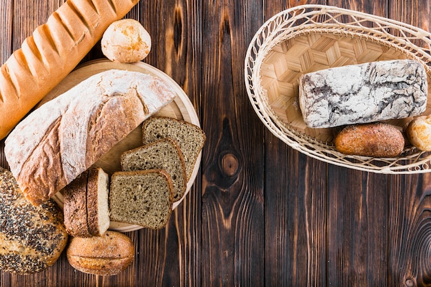 Free photo variety of freshly baked breads on plate and basket over the wooden backdrop