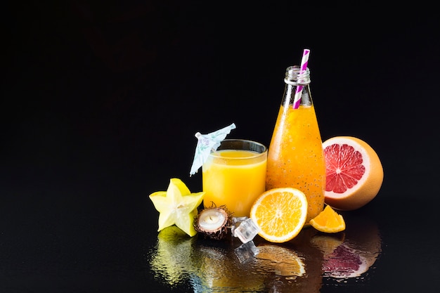 Free Photo variety of fruit and juices on black background