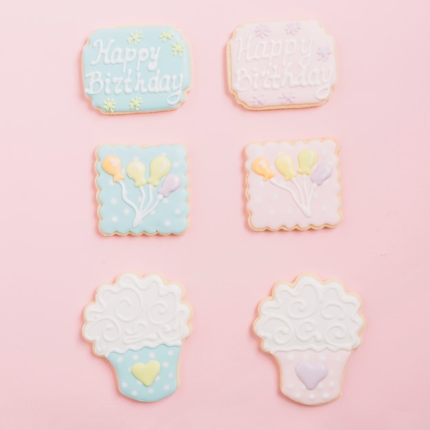 Variety of gingerbread icing cookies arranged on pink background