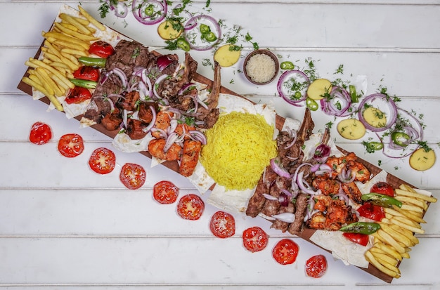 Variety of meat kebab with grilled vegetables and salad on the white table