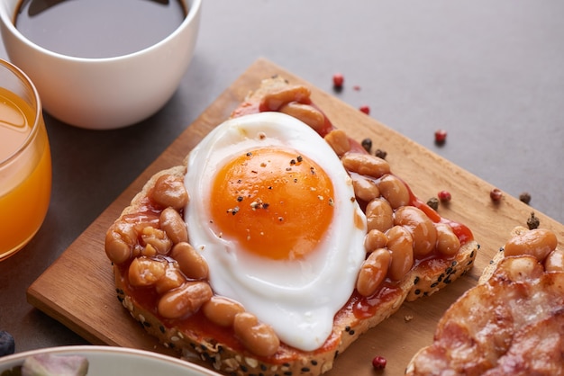 Free photo variety of open sandwiches made of brown whole wheat  bread with tomatoes sauce, white beans, bacon, fried egg.