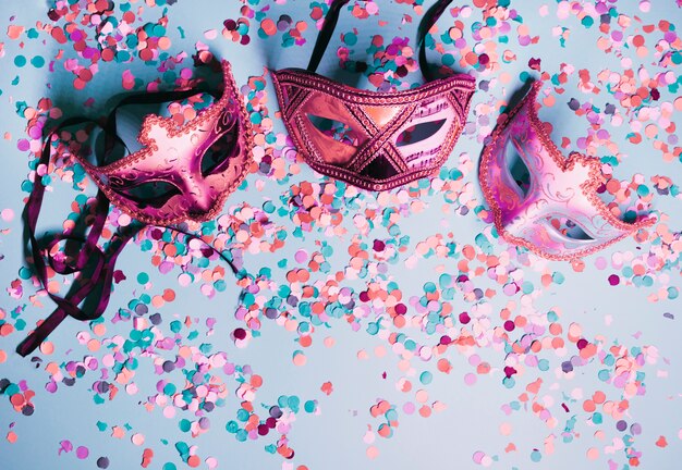 Variety of party eye mask with colorful confetti on blue backdrop