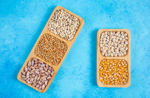 Variety of raw beans on blue background.