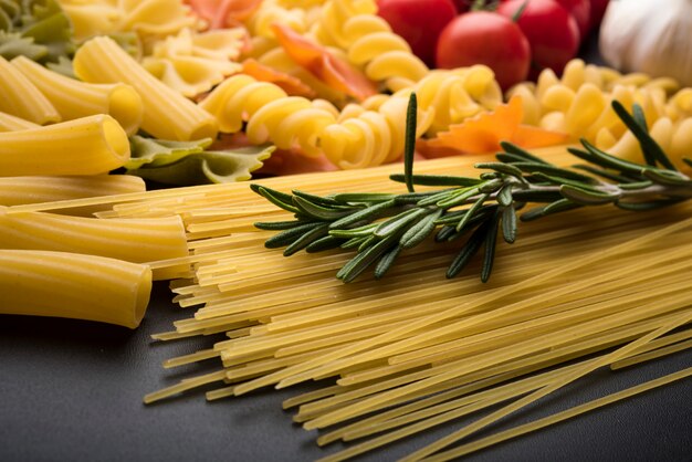 Variety of uncooked pasta on black background