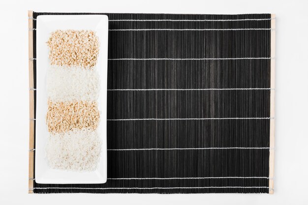 Variety of uncooked rice in white tray on black placemat