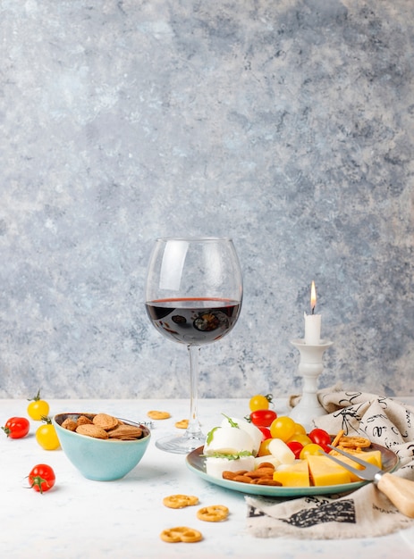 Free Photo various cheese and cheese plate on light table with different nuts and fruits and glass of wine