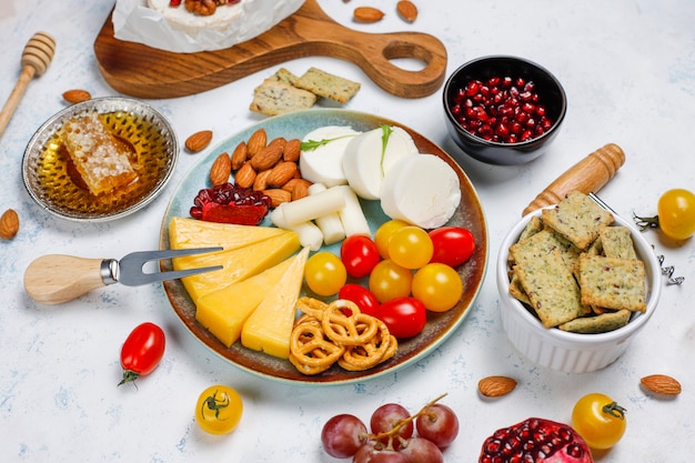 Free photo various cheese and cheese plate on light table with different nuts and fruits