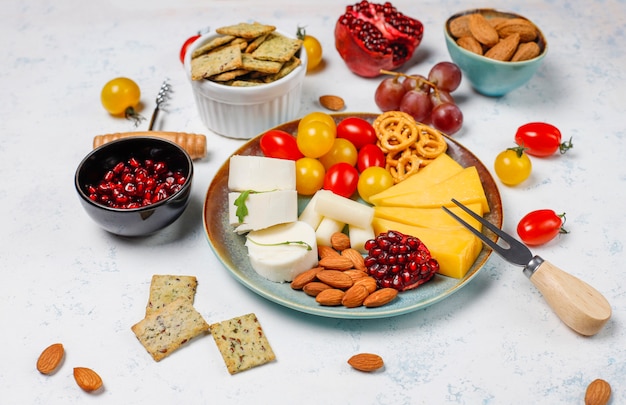 Free photo various cheese and cheese plate on light table with different nuts and fruits