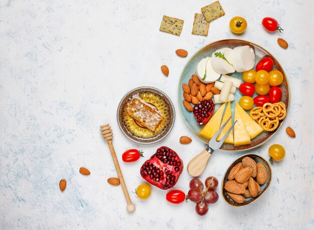 Various cheese and cheese plate on light table with different nuts and fruits