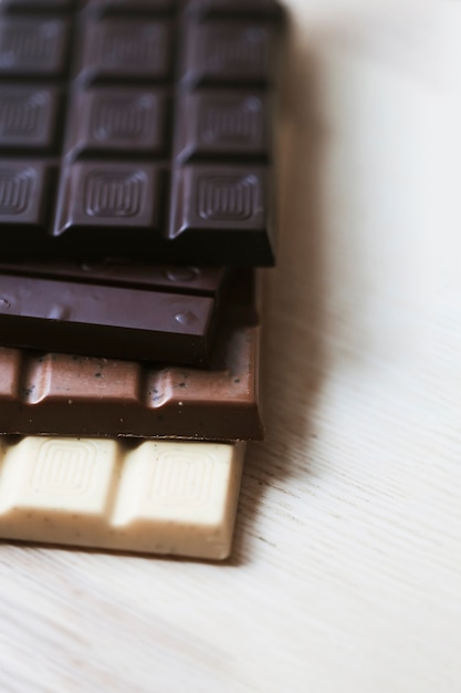 Free photo various chocolate bar stack on wooden textured backdrop