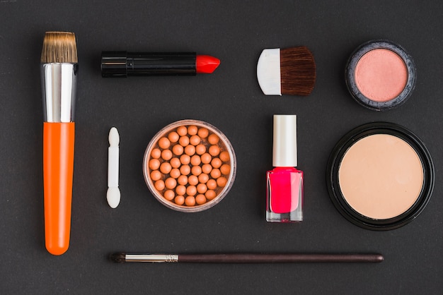 Free photo various cosmetic products and makeup brushes on black background