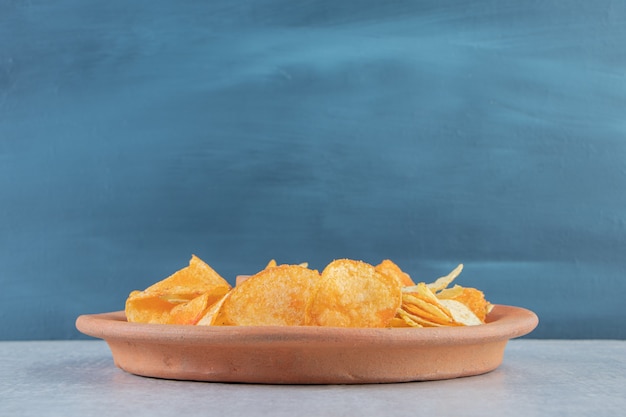 Various crispy chips placed on plate on stone.