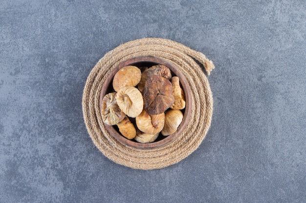 Various dried fruits in a bowl on a trivet , on the marble background.