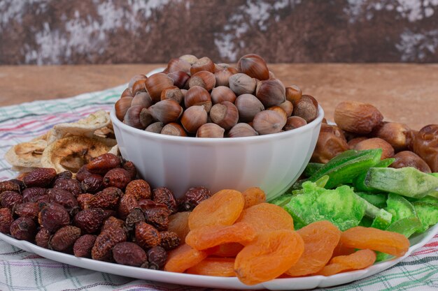 Various dried fruits and nuts on white plate.