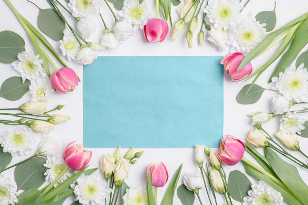 Various flowers around blue paper