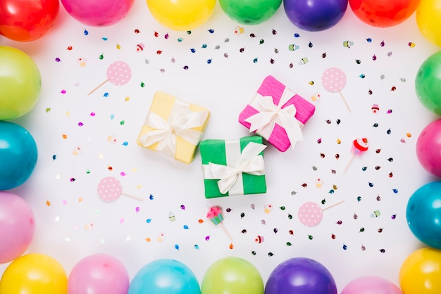 Free photo various gift boxes decorated with confetti; props and balloons on white background