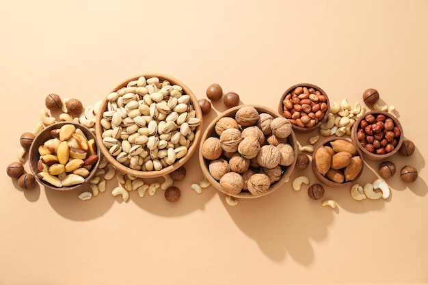 Free Photo various nuts in wooden bowls on a beige background