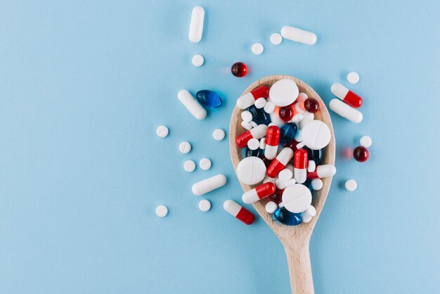 Various pills on wooden spoon