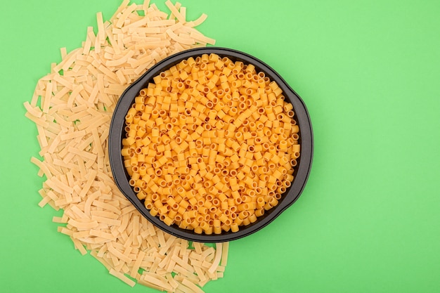 various shaped pasta top view on green surface