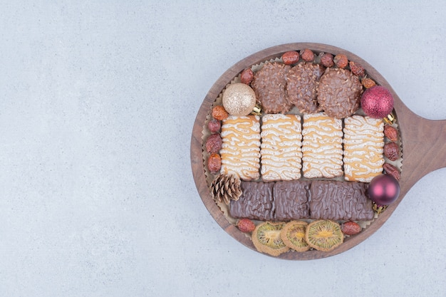 Various snacks and Christmas balls on wooden board. 