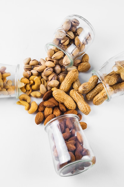 Various spilled dried fruits from jar on white background